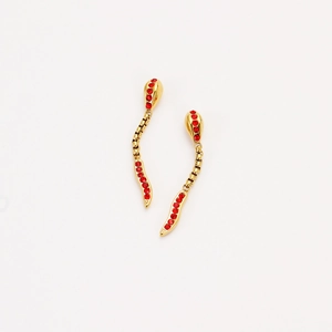 Macro view of gold snake earrings with red zircon stones on a white background