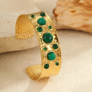 Détail d'un bracelet manchette doré martelé avec incrustations de pierres naturelles vertes
