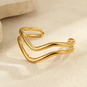 Brazalete ondulado de doble capa en acero inoxidable dorado sobre fondo de piedra