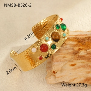 Détail d'un bracelet vintage en acier doré avec texture martelée et pierres colorées