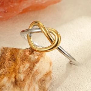 Anillo de nudo bicolor con acabados en oro y plata sobre una superficie de piedra