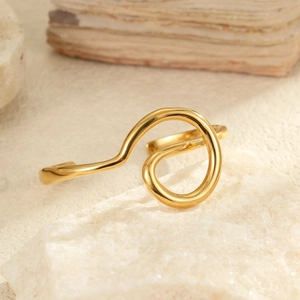 Vista detallada de un brazalete dorado ondulado sobre una base de piedra mineral texturizada