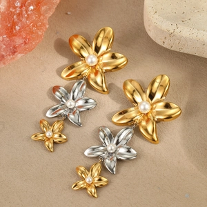 Élégantes boucles d'oreilles fleuries bicolores or et argent avec perles sur fond texturé