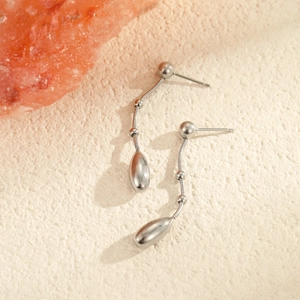 Detailweergave van minimalistische zilveren druppeloorbellen met een elegante slangenketting