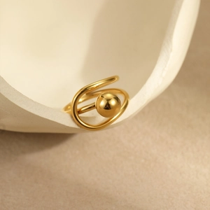Macro detail of a minimalist gold bow ring with oval pearl on a ceramic stand