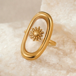 Macro detail of a golden ring featuring a sun motif inside a clear resin oval frame