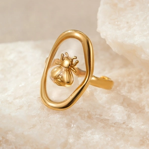 Macro detail of a 3D gold bee embedded in a transparent oval frame on a vintage ring