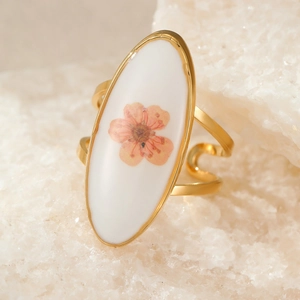 Macro shot of gold oval ring featuring pink dried flowers and hollow wavy band detail