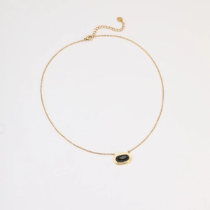 Detail van 18K vergulde kabelketting met zwarte onyx hanger en ovaal logo label
