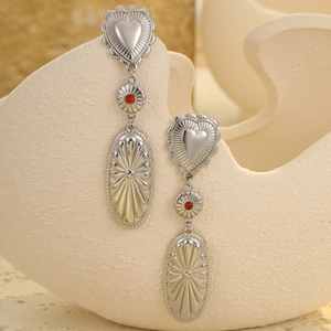 Detailed shot of vintage silver heart earrings with red beads on a stone display