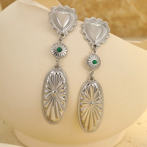 Detail of vintage heart earrings with green stone and embossed textures on ceramic