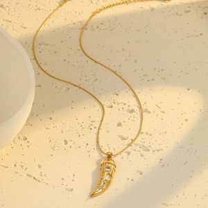 Detail of gold horn pendant necklace with sparkling white zircons on a snake chain