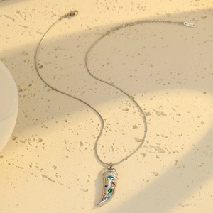 Macro shot of silver horn pendant with colored zircon stones on a snake chain