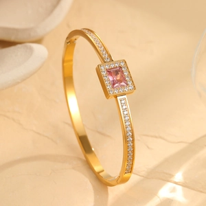 Detail of gold open bangle featuring rectangular pink zircon and pavé setting