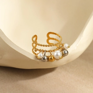 Macro detail of triple-layered gold bead ring with pearl and metal sphere charms