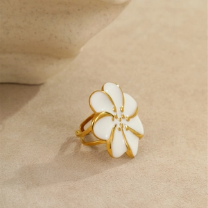 Primer plano detallado de un anillo de flor de esmalte blanco con acabado dorado