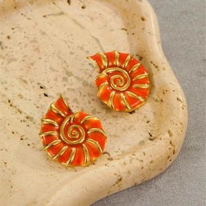 Detail of 18K gold-plated shell earrings with bright orange enamel and spiral texture