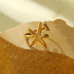 Dettaglio macro dell'anello a stella marina dorata con texture puntinata su pietra
