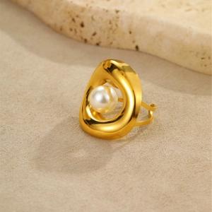 Dettaglio dell'anello a conchiglia dorato con design irregolare e perla bianca incastonata