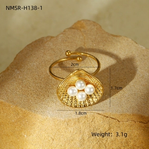 Vista macro dettagliata di un anello a conchiglia dorato con quattro eleganti perle bianche