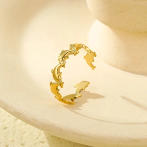 Anello aperto con delfini in oro 18K lucido su un piatto in ceramica beige