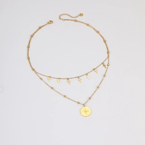 Détail d'un collier doré double couche avec petites croix et pendentif étoile polaire