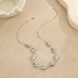 Vue détaillée du collier en métal argenté avec pendentifs sphériques à texture en spirale