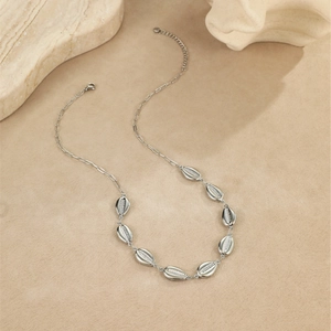 Détail du collier argenté avec pendentifs étoile de mer et coquillage sur sable fin