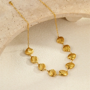 Détail du collier coquillages en acier inoxydable plaqué or 18k sur un fond en pierre texturé