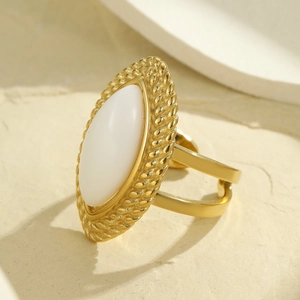 Makroaufnahme eines goldenen Vintage-Ringes mit weißem Stein und verzierter Ringschiene