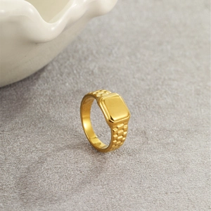 Macro shot of gold square signet ring with embossed watchband texture on the sides