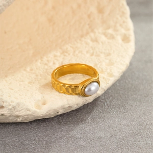 Detailed macro shot of a gold-plated gear ring featuring an elegant oval pearl inlay