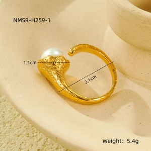 Detalle de anillo dorado martillado con perla de 1,1 cm sobre bandeja de cerámica