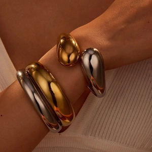 Polished teardrop bangle set in gold and silver finish with organic metallic flow