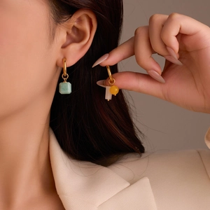 Detail von Vintage-Goldohrringen mit grünem Stein und Sternanhängern am Model
