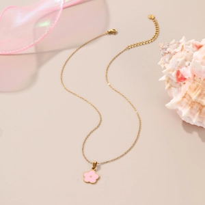 Detail of a gold-plated necklace featuring a pink enamel flower pendant on silk ribbon