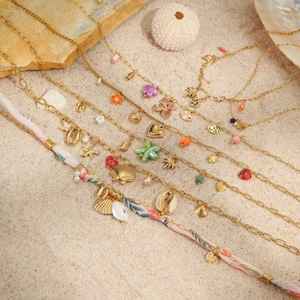 Bohemian gold stainless steel necklace set with sea star and shell charms on beach sand