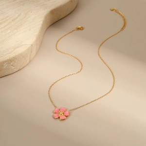 Detailed macro view of a gold chain necklace with a pink enamel flower pendant