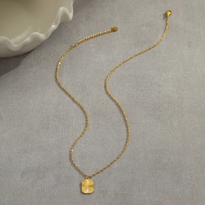 Detail of gold stainless steel necklace with square sunburst pendant and lobster clasp