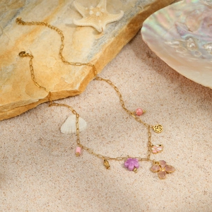 Macro shot of gold ocean flower necklace with starfish and shells on beach sand