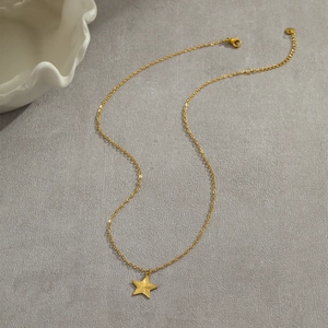 Detail shot of golden stainless steel necklace featuring a star pendant with radial texture