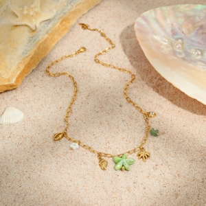 Golden ocean theme necklace with starfish shell and palm tree charms on beach sand