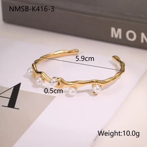 Detailed view of irregular wave gold bangle with white pearls including size measurements