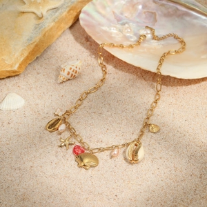 Detailed shot of golden marine charms with starfish and pearls on a sandy beach setting