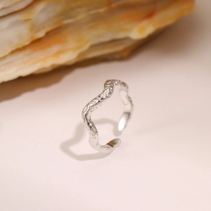Macro shot of silver titanium steel ring featuring irregular molten texture and open band