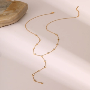 Elegante collar en Y de acero inoxidable dorado con borlas de circón sobre fondo beige