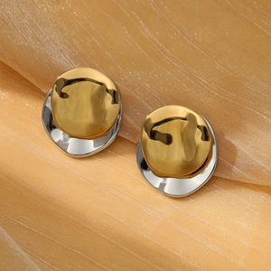 Makroaufnahme geometrischer zweifarbiger Ohrringe in Gold und Silber auf Seidenstoff