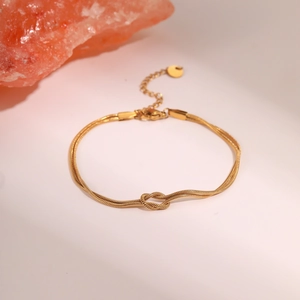 Dubbele gouden slangenketting armband met een centraal knoopontwerp en verlengstukje