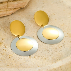 Detail von geometrischen zweifarbigen Ohrringen mit Gold und Silbermatt-Finish auf Sandstein