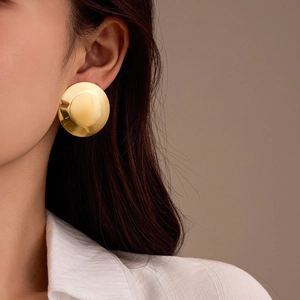 Nahaufnahme eines Models mit großen polierten goldenen geometrischen Scheibenohrringen